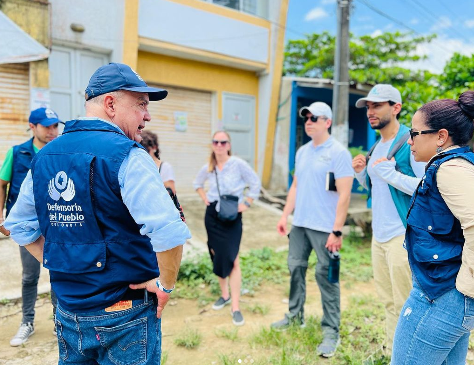 Man in Defensoria el Pueblo Colombia vest talking to a group of people standing in a circle. 